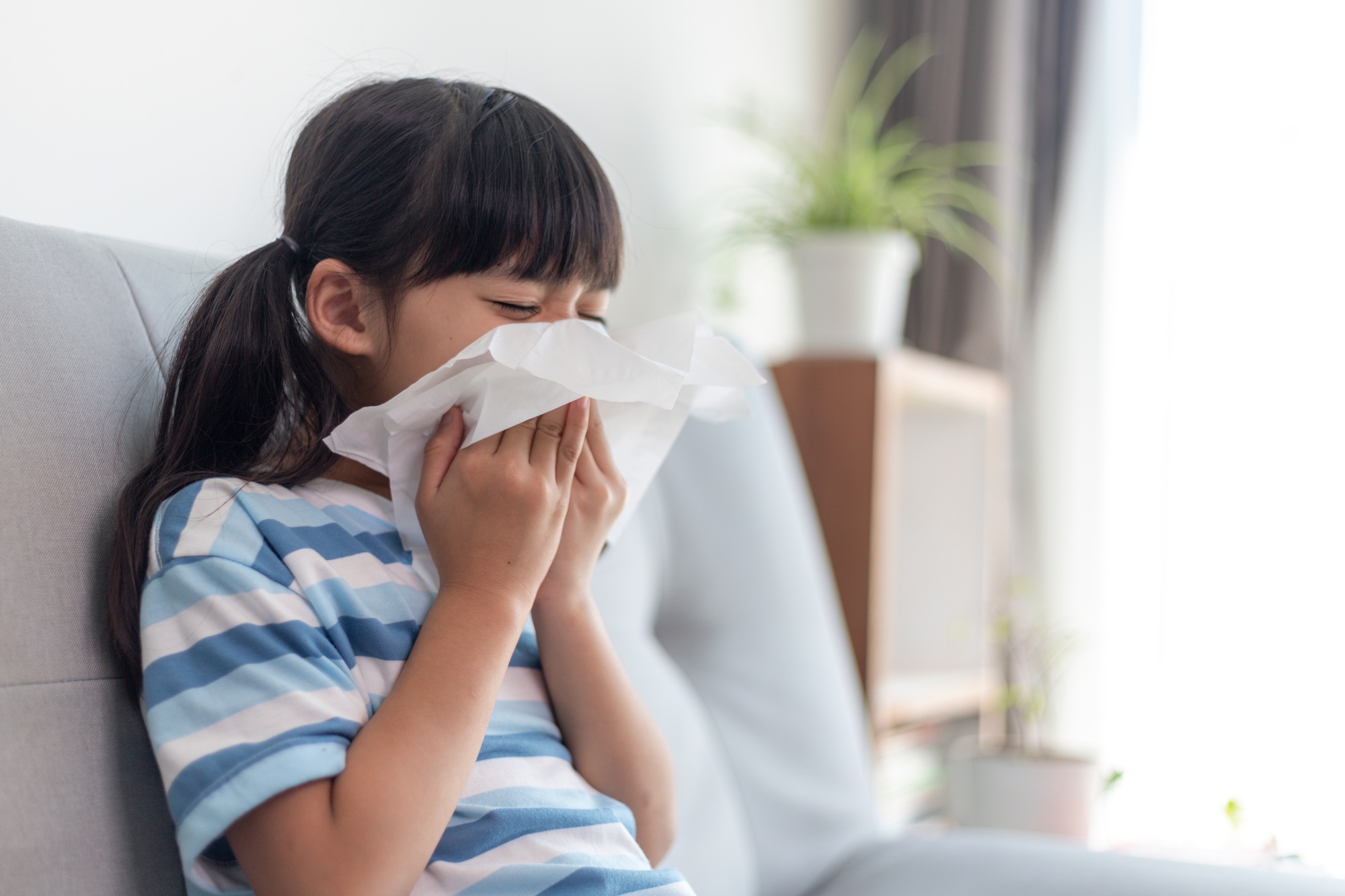 Unhealthy kid blowing nose into tissue, Child suffering from running nose or sneezing,