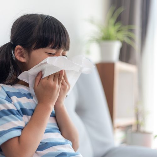 Unhealthy kid blowing nose into tissue, Child suffering from running nose or sneezing,